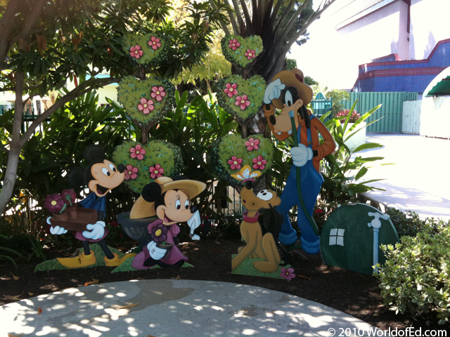 Wooden cutouts of Disney characters in front of shrubs.