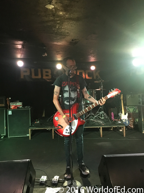 Mikey Ergs singing and playing guitar on stage.