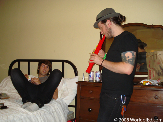 Atom and Mike in the hotel room playing instruments.
